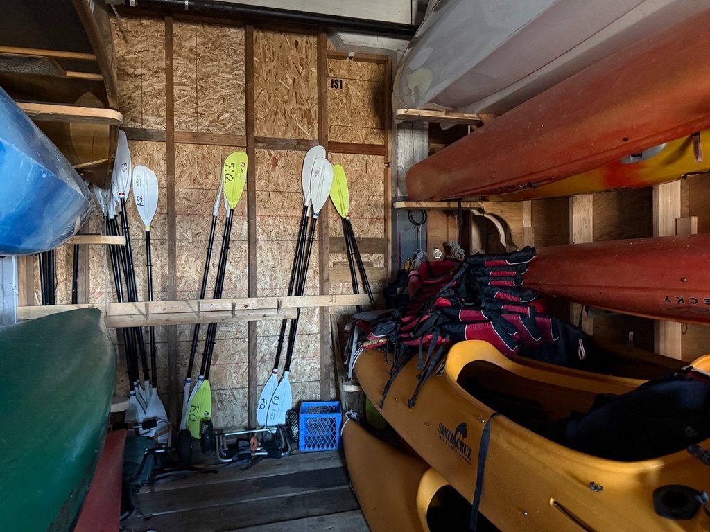 Racked kayaks, a canoe, paddles and life vests in the Fisherman's Quay kayak room