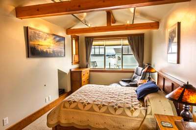 Private bedroom in The Loft with a queen bed under a sloped timber ceiling and a window over the channel