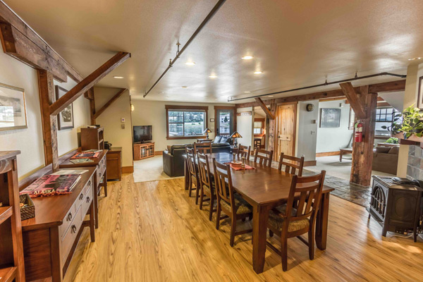 Long family style dining table under exposed timber trusses in The Loft, set for a group meal