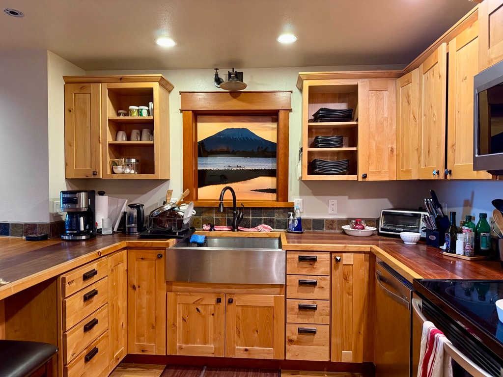 Kitchen counter in The Loft with a stainless farmhouse sink, Ironwood counter tops and a framed Mount Edgecumbe photograph above