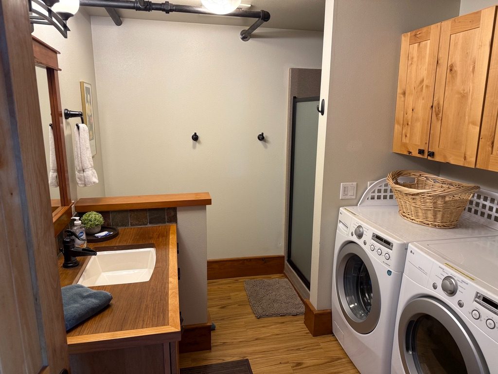 Laundry and shower room in The Loft with a washer, dryer, vanity and glass shower
