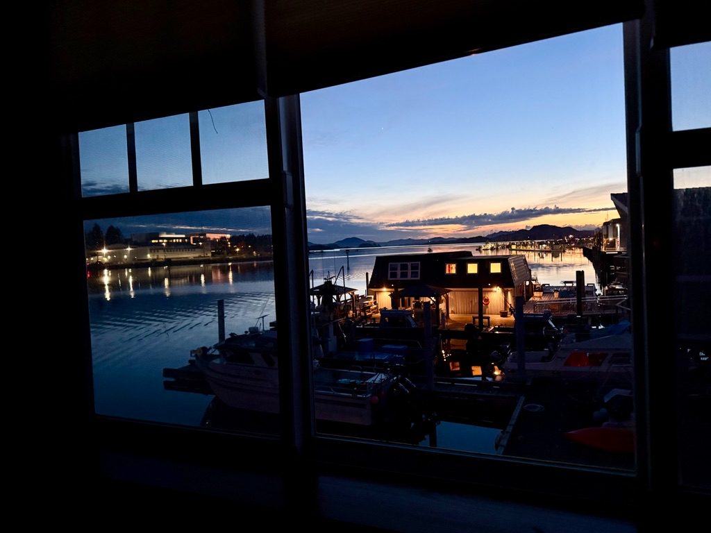 Night view from a window in The Loft over the lit dock, moored boats and the channel beyond