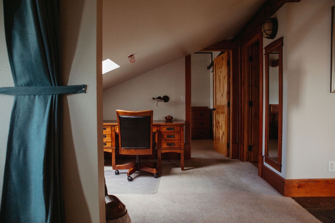 Office nook under a skylight in The Loft, with a wooden desk and chair beside the bedroom doors