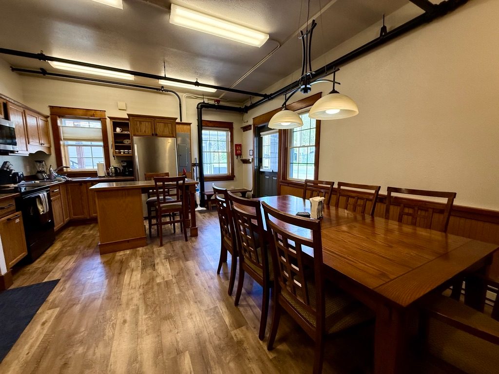 Kitchen and long dining table in the North Bunkhouse under pendant lights, with a breakfast bar between them