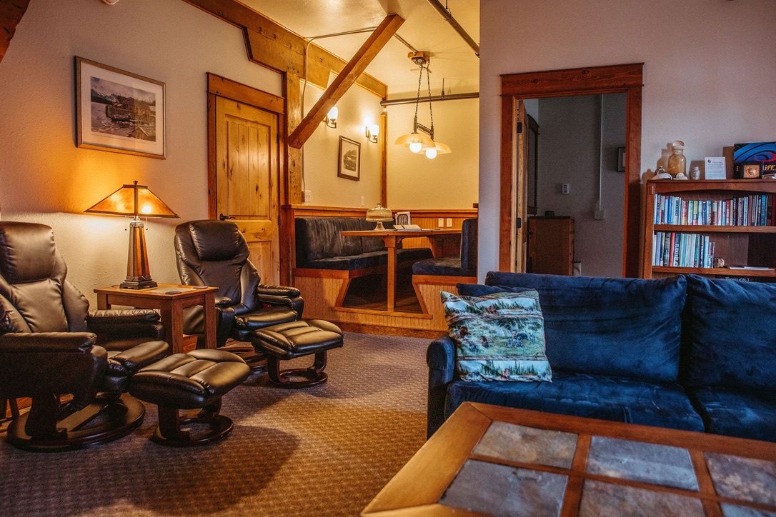 Lounge in the South Bunkhouse with leather recliners, a blue sofa and the dining booth visible through the doorway